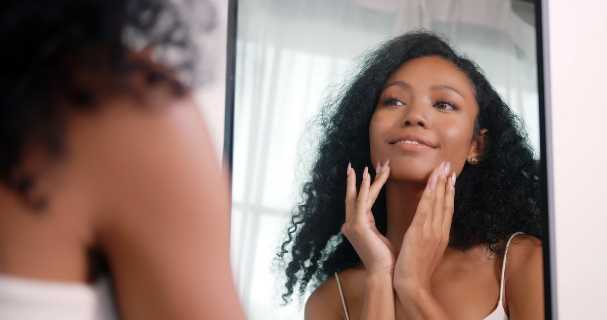 woman holding hands up to face, smiling in a mirror